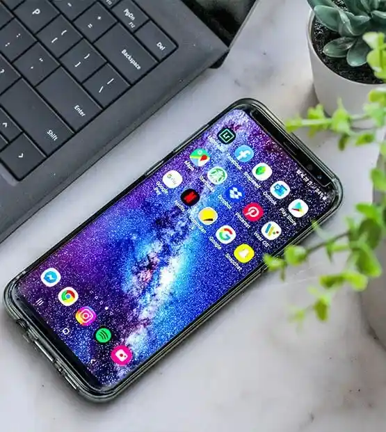 Smartphone with a galaxy wallpaper displaying multiple app icons on its screen